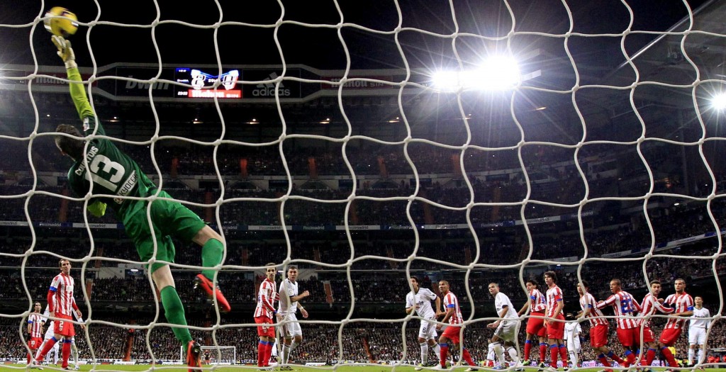 epa03493602 Atletico Madrid's Belgian goalkeeper Thibaut Courtois (L) tries to stop a shot from Portuguese forward Cristiano Ronaldo of Real Madrid during their Spanish Liga's Primera Division match at Santiago Bernabeu stadium in Madrid, central Spain, 01 December 2012. EPA/JUANJO MARTIN