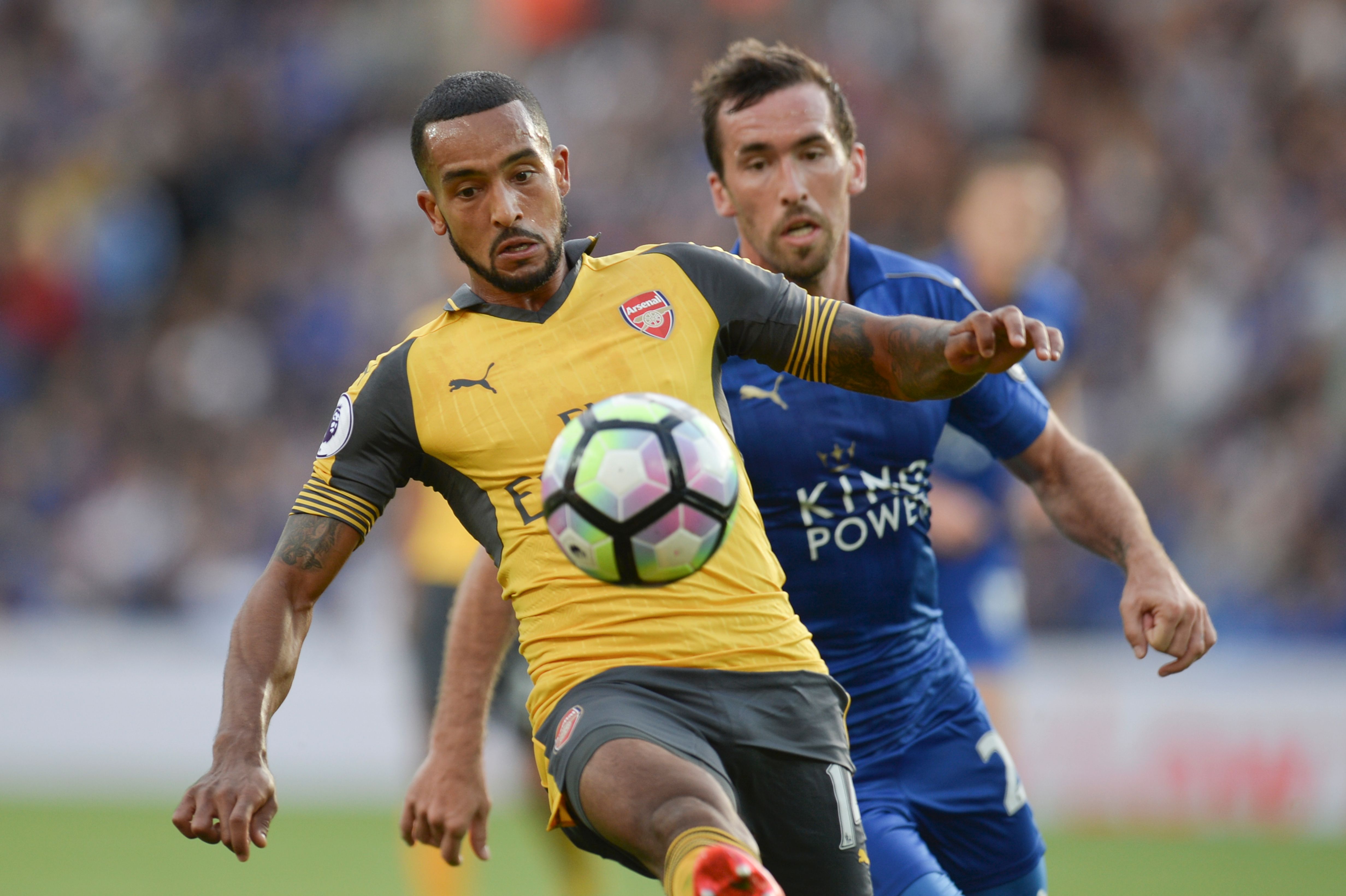 Arsenal's English midfielder Theo Walcott (L) tries to hold off Leicester City's Austrian defender Christian Fuchs (R) during the English Premier League football match between Leicester City and Arsenal at King Power Stadium in Leicester, central England on August 20, 2016. (Photo credit: Oli Scarff/AFP/Getty Images)