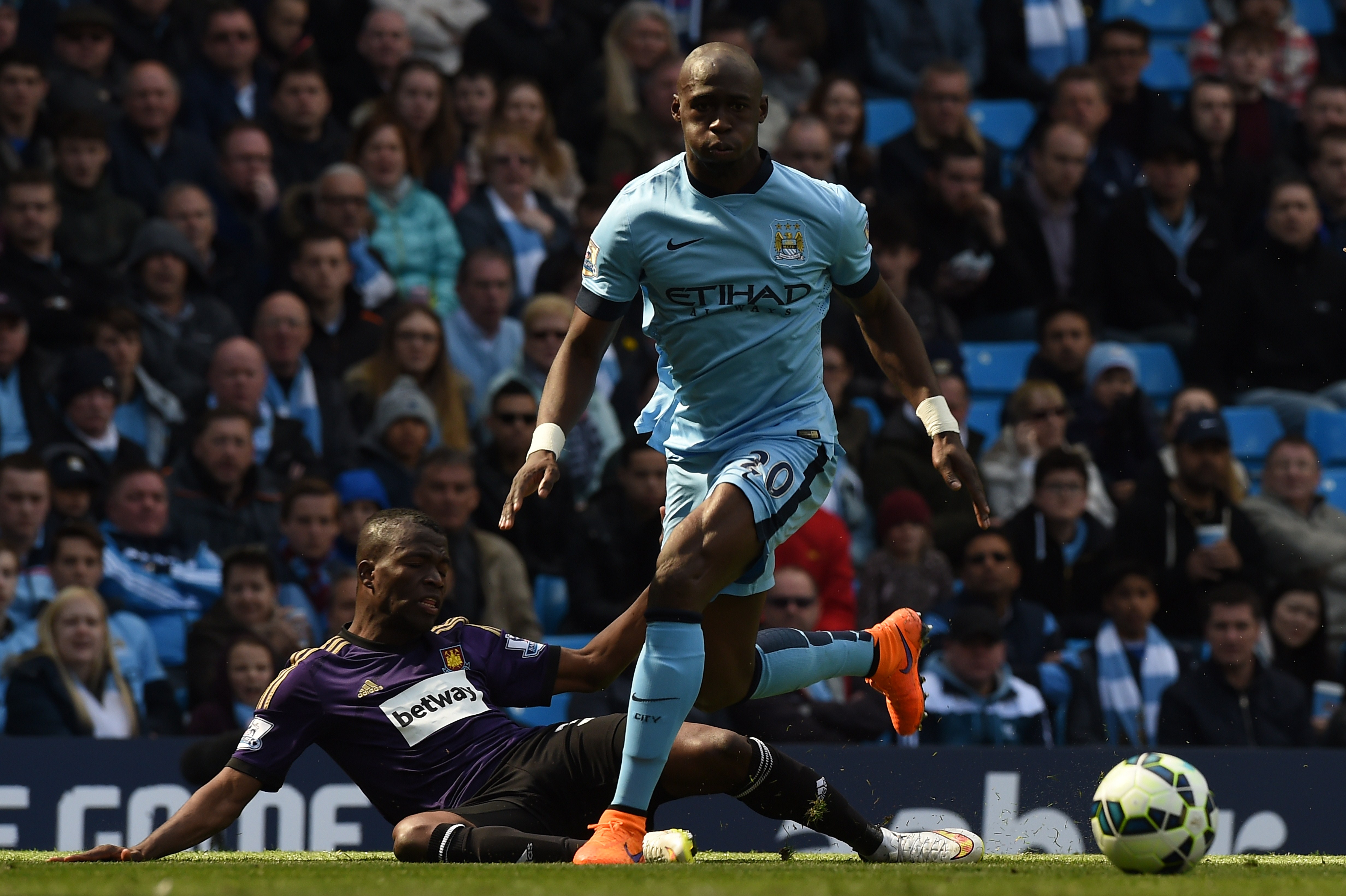 Manchester City's French defender Eliaquim Mangala (R) beats West Ham United's Cameroonian midfielder Alex Song (L) during the English Premier League football match between Manchester City and West Ham United at the Etihad Stadium in Manchester, north west England on April 19, 2015. AFP PHOTO / PAUL ELLIS RESTRICTED TO EDITORIAL USE. No use with unauthorized audio, video, data, fixture lists, club/league logos or live services. Online in-match use limited to 45 images, no video emulation. No use in betting, games or single club/league/player publications. (Photo credit should read PAUL ELLIS/AFP/Getty Images)