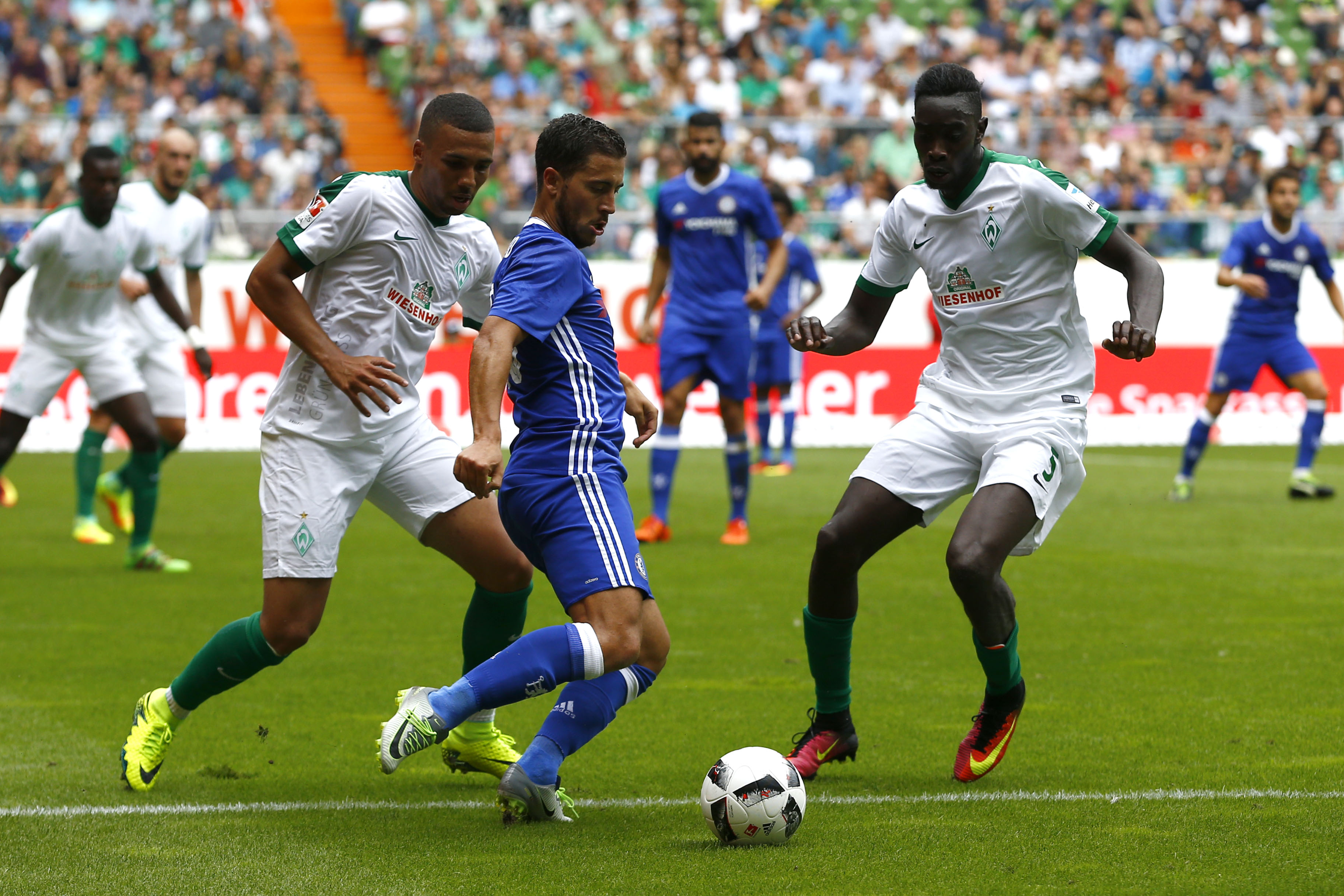 BREMEN, GERMANY - AUGUST 07: Leon Guwara and Sambou Yatabare of Bremen challenges Eden Hazard of Chelsea during the pre-season friendly match between Werder Bremen and FC Chelsea at Weserstadion on August 7, 2016 in Bremen, Germany. (Photo by Joachim Sielski/Bongarts/Getty Images)