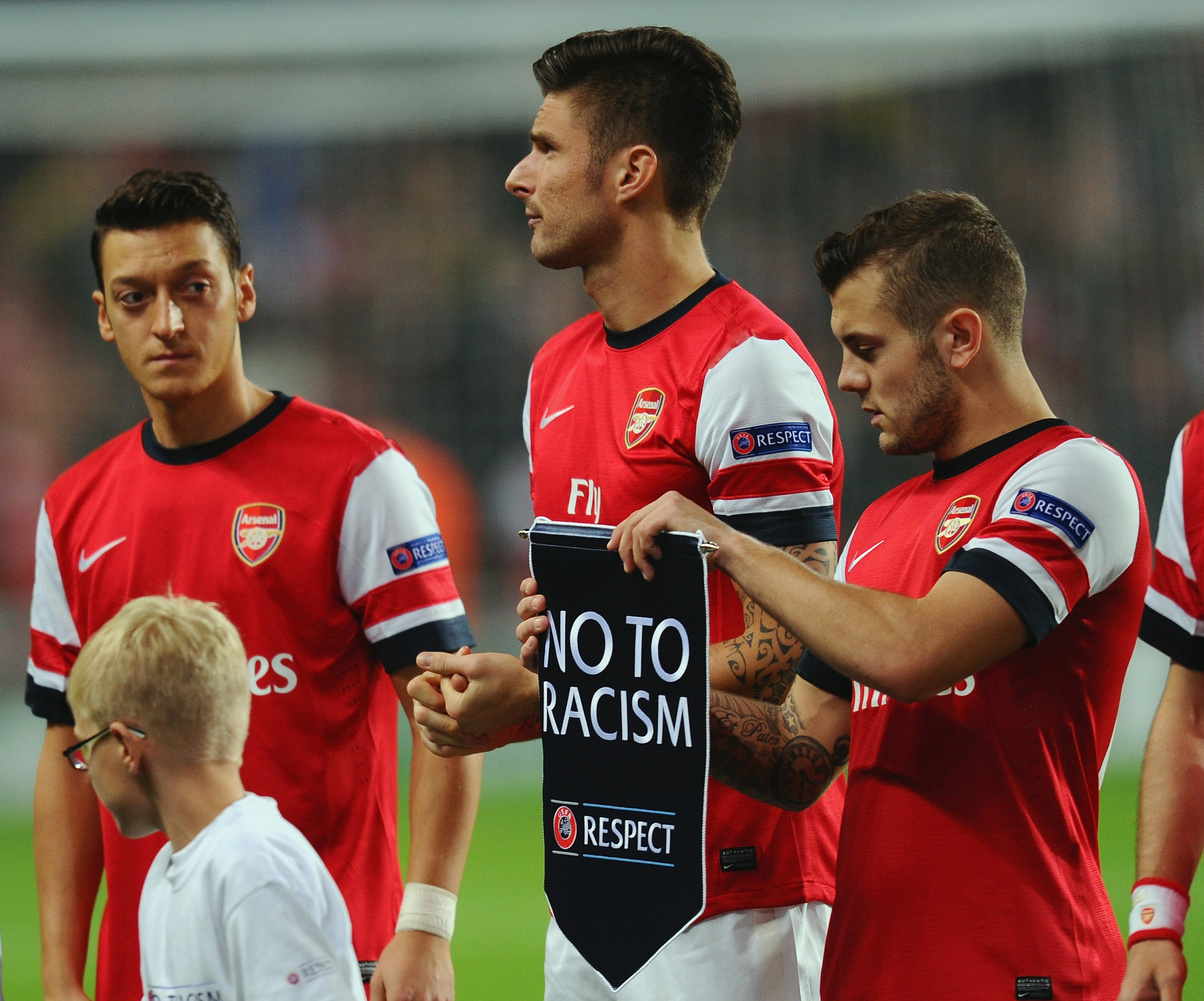 LONDON, ENGLAND - OCTOBER 22: Jack Wilshere of Arsenal prepares to hand the 'No to Racism' pennant to Olivier Giroud of Arsenal during the UEFA Champions League Group F match between Arsenal and Borussia Dortmund at Emirates Stadium on October 22, 2013 in London, England. (Photo by Mike Hewitt/Bongarts/Getty Images)