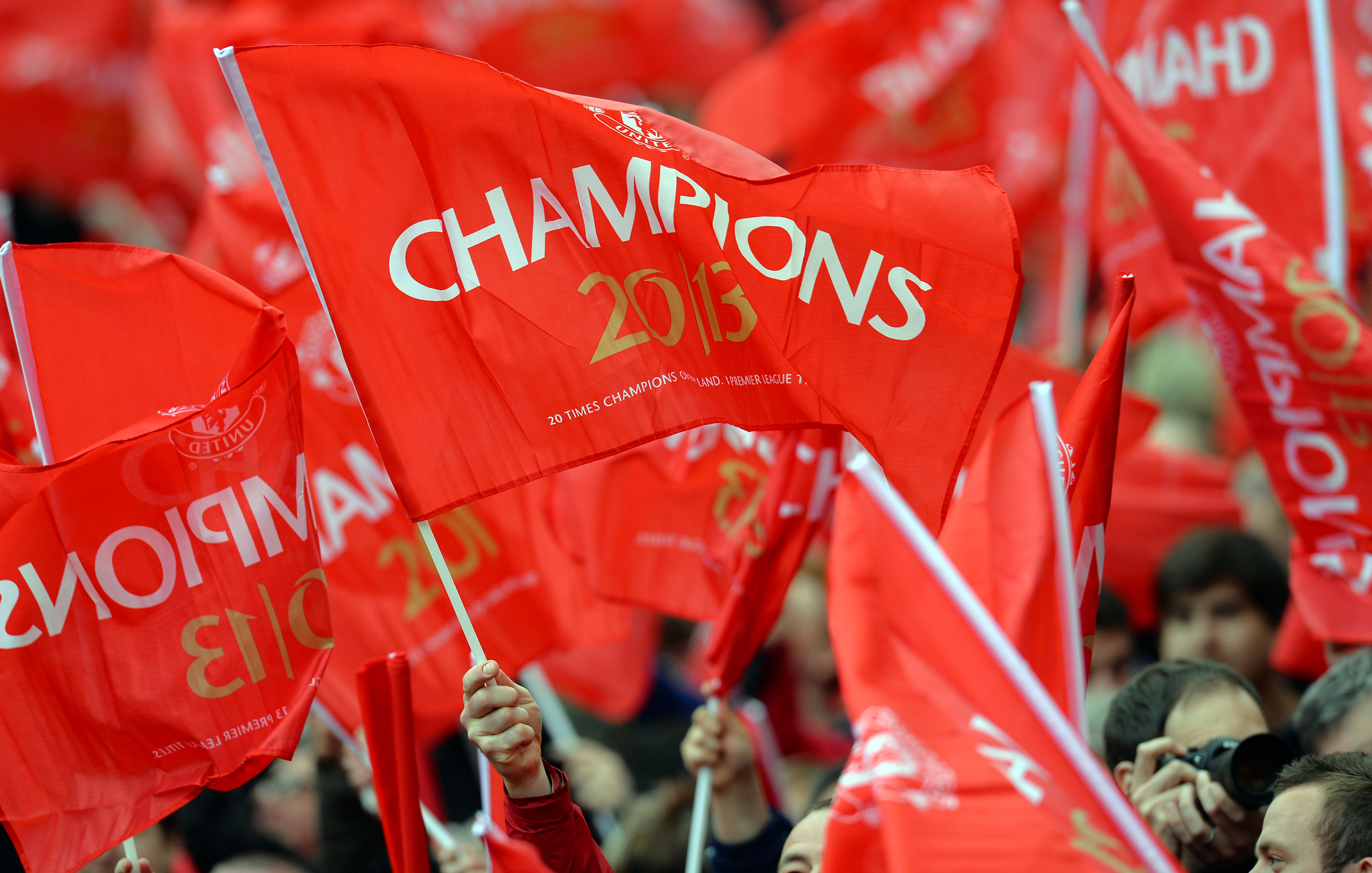 Supports hold red 'champions' flags during the English Premier League football match between Manchester United and Swansea City at Old Trafford in Manchester, northwest England, on May 12, 2013. (Photo by Andrew Yates/AFP/Getty Images)