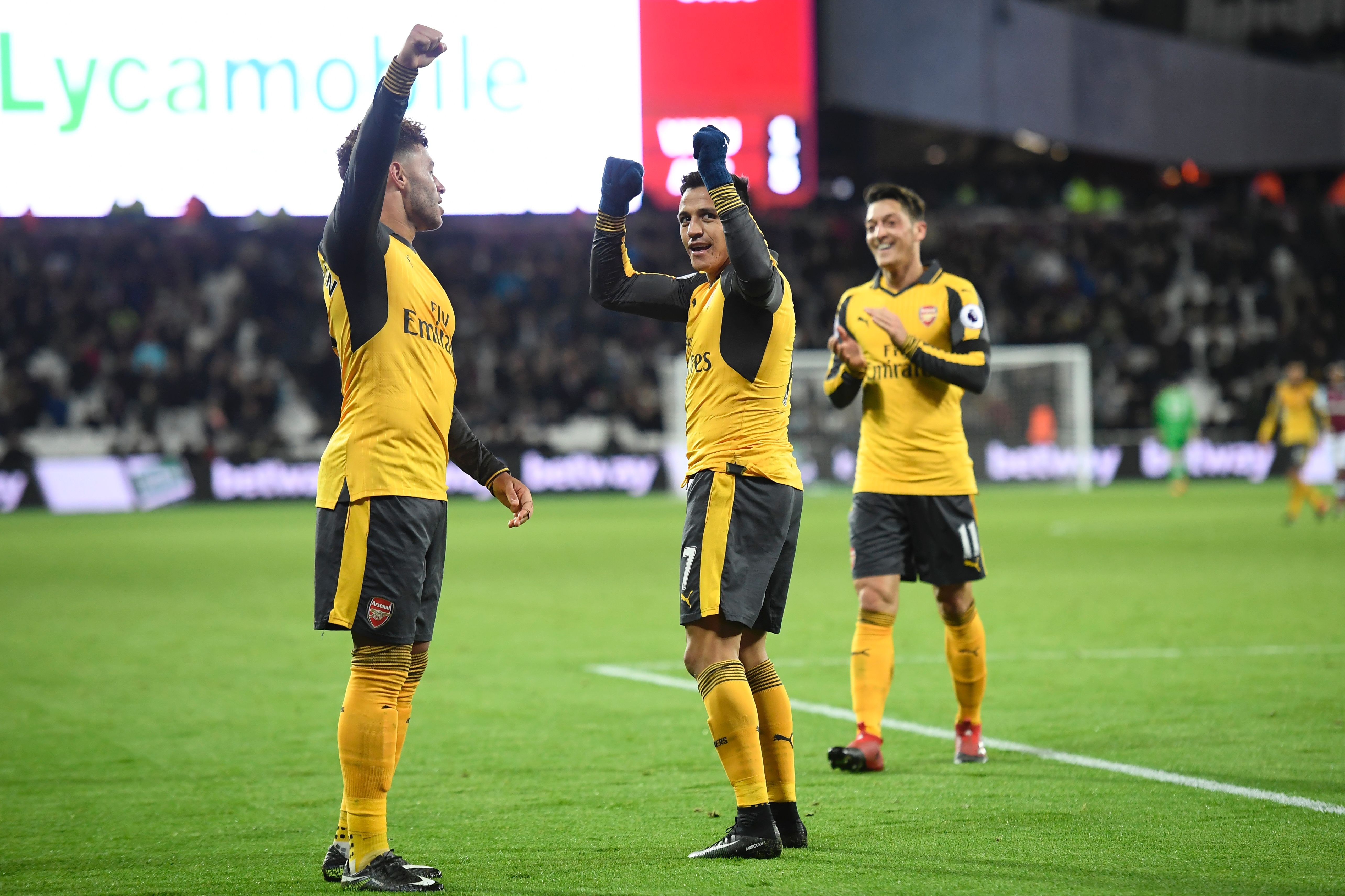 The three goal-scorers, Arsenal's English midfielder Alex Oxlade-Chamberlain (L), Arsenal's Chilean striker Alexis Sanchez (C) and Arsenal's German midfielder Mesut Ozil (R) celebrate Sanchez's third goal, the team's fifth, during the English Premier League football match between West Ham United and Arsenal at The London Stadium, in east London on December 3, 2016.
Arsenal won the game 5-1. / AFP / Justin TALLIS / RESTRICTED TO EDITORIAL USE. No use with unauthorized audio, video, data, fixture lists, club/league logos or 'live' services. Online in-match use limited to 75 images, no video emulation. No use in betting, games or single club/league/player publications. / (Photo credit should read JUSTIN TALLIS/AFP/Getty Images)