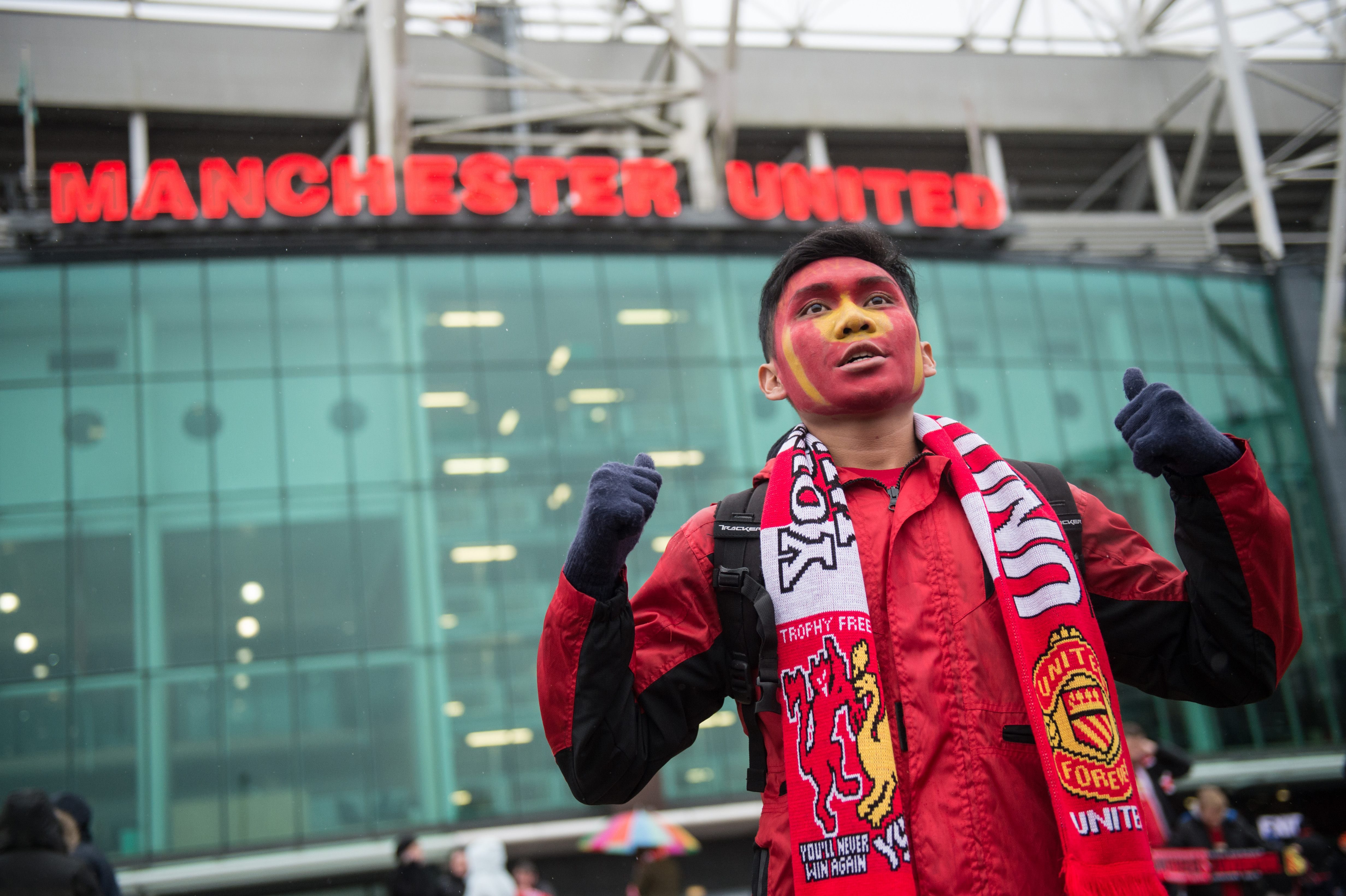 a Manchester United fan poses for a photograph outside the stadium ahead of the English Premier League football match between Manchester United and Liverpool at Old Trafford in Manchester, north west England, on January 15, 2017. / AFP / OLI SCARFF / RESTRICTED TO EDITORIAL USE. No use with unauthorized audio, video, data, fixture lists, club/league logos or 'live' services. Online in-match use limited to 75 images, no video emulation. No use in betting, games or single club/league/player publications. / (Photo credit should read OLI SCARFF/AFP/Getty Images)