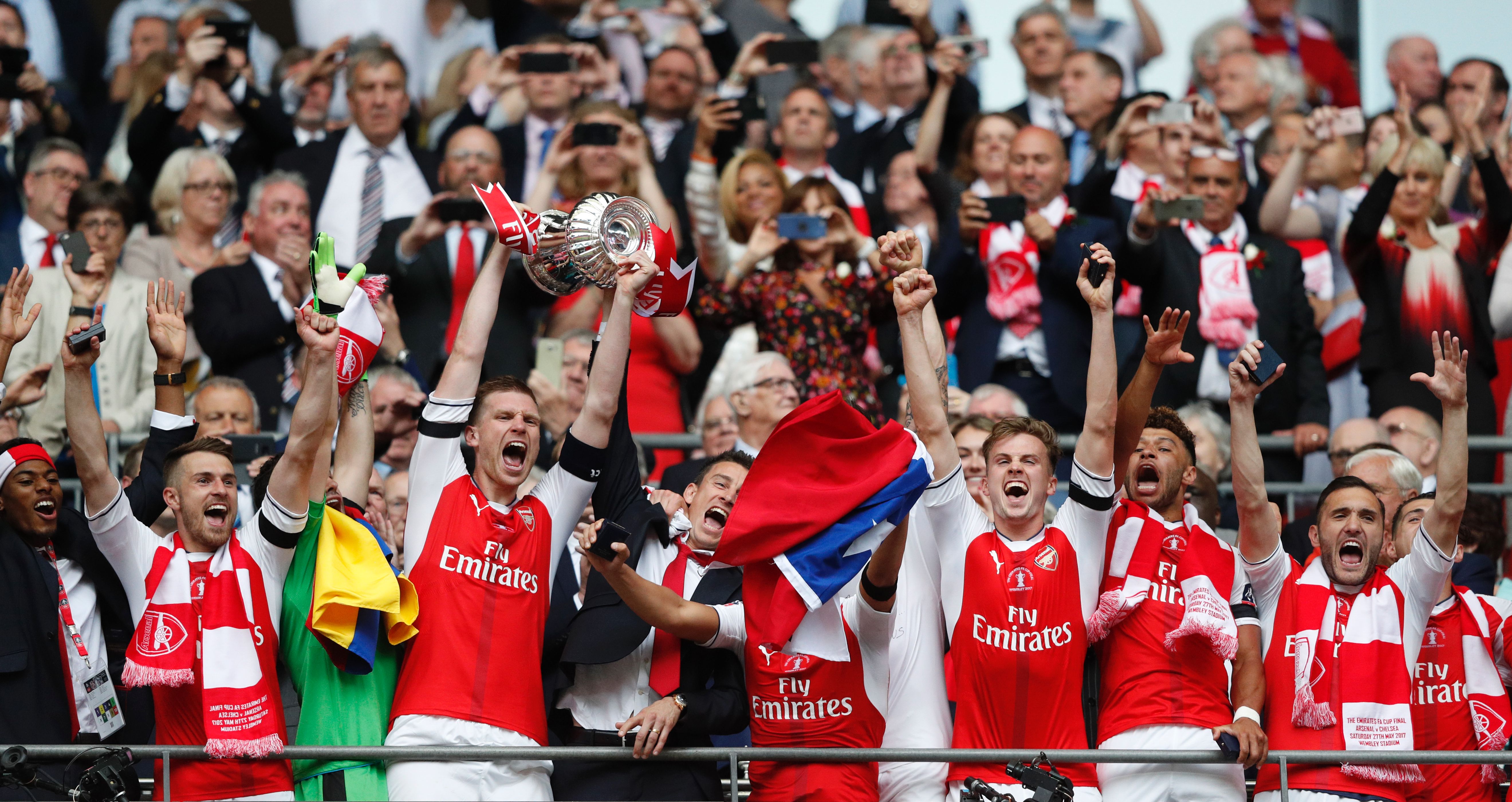 Arsenal's German defender Per Mertesacker lifts the FA Cup trophy as Arsenal players celebrate their victory over Chelsea in the English FA Cup final football match between Arsenal and Chelsea at Wembley stadium in London on May 27, 2017.
Aaron Ramsey scored a 79th-minute header to earn Arsenal a stunning 2-1 win over Double-chasing Chelsea on Saturday and deliver embattled manager Arsene Wenger a record seventh FA Cup. / AFP PHOTO / Adrian DENNIS / NOT FOR MARKETING OR ADVERTISING USE / RESTRICTED TO EDITORIAL USE        (Photo credit should read ADRIAN DENNIS/AFP/Getty Images)