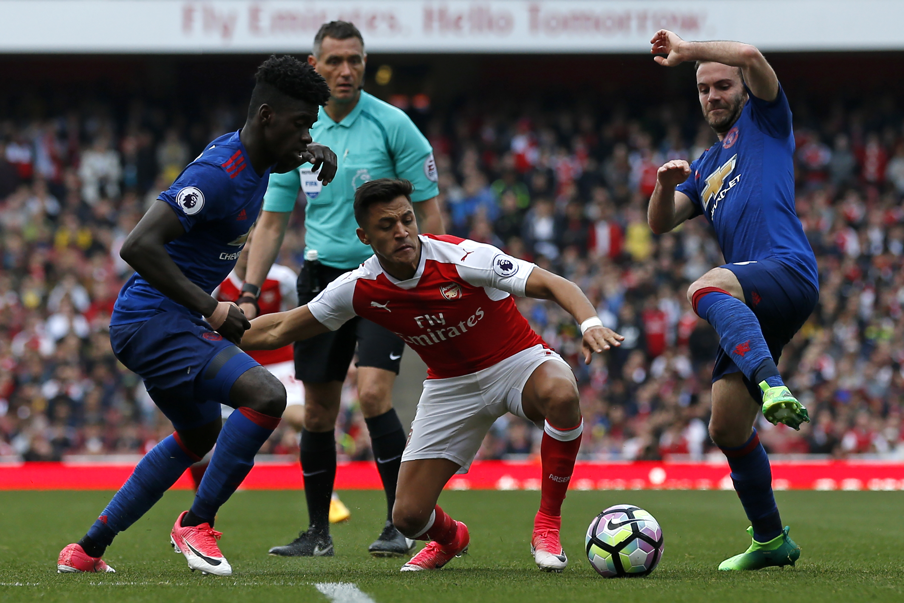 Arsenal's Chilean striker Alexis Sanchez (C) vies with Manchester United's DR Congo-born defender Axel Tuanzebe (L) and Manchester United's Spanish midfielder Juan Mata (R) during the English Premier League football match between Arsenal and Manchester United at the Emirates Stadium in London on May 7, 2017.
Arsenal won the game 2-0. / AFP PHOTO / IKIMAGES / Ian KINGTON / RESTRICTED TO EDITORIAL USE. No use with unauthorized audio, video, data, fixture lists, club/league logos or 'live' services. Online in-match use limited to 45 images, no video emulation. No use in betting, games or single club/league/player publications. / (Photo credit should read IAN KINGTON/AFP/Getty Images)