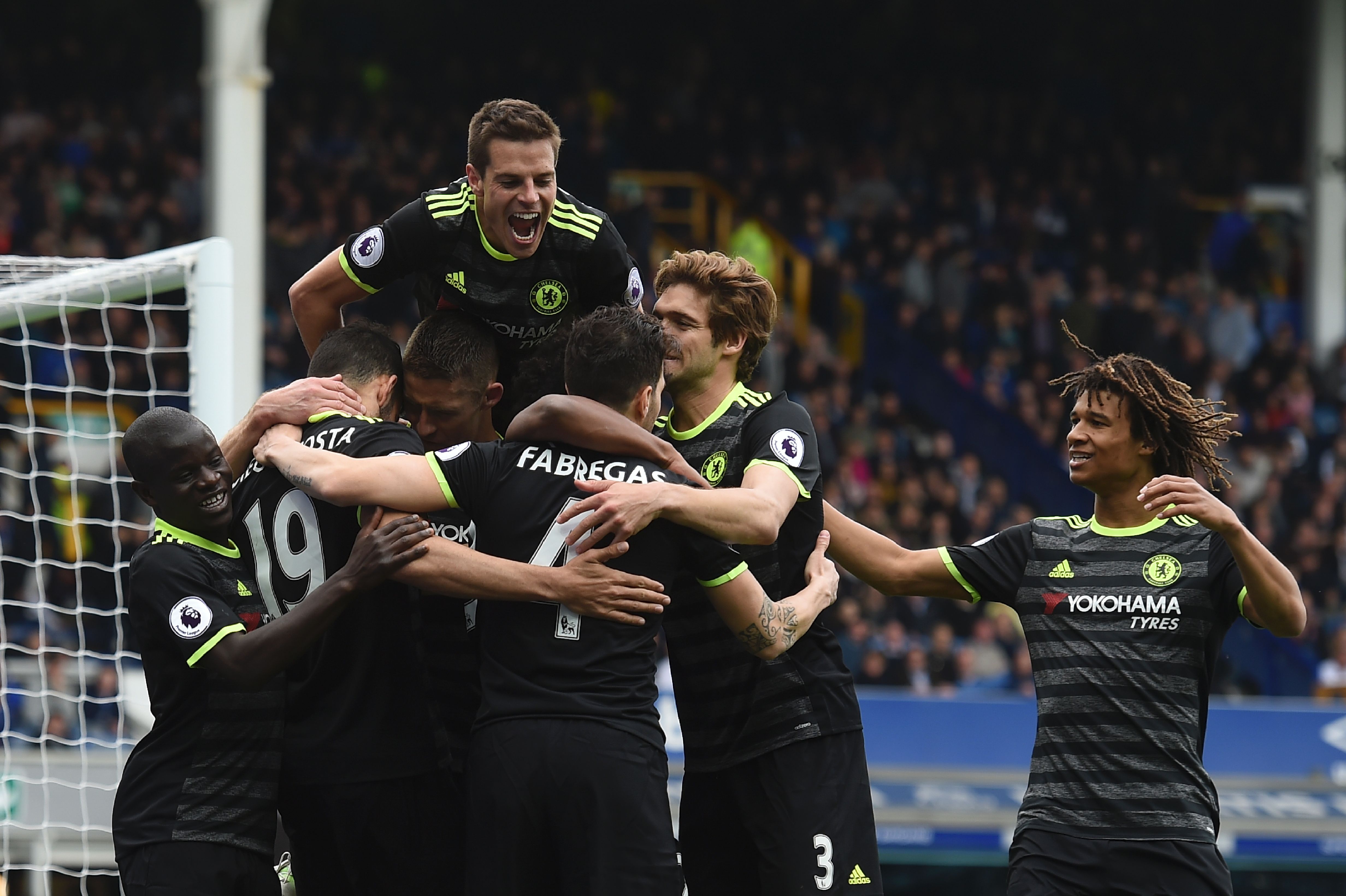 Chelsea's Spanish defender Cesar Azpilicueta (top C) jumps onto the celebration after Chelsea's Brazilian midfielder Willian scored their third goal during the English Premier League football match between Everton and Chelsea at Goodison Park in Liverpool, north west England on April 30, 2017. / AFP PHOTO / PAUL ELLIS / RESTRICTED TO EDITORIAL USE. No use with unauthorized audio, video, data, fixture lists, club/league logos or 'live' services. Online in-match use limited to 75 images, no video emulation. No use in betting, games or single club/league/player publications. / (Photo credit should read PAUL ELLIS/AFP/Getty Images)