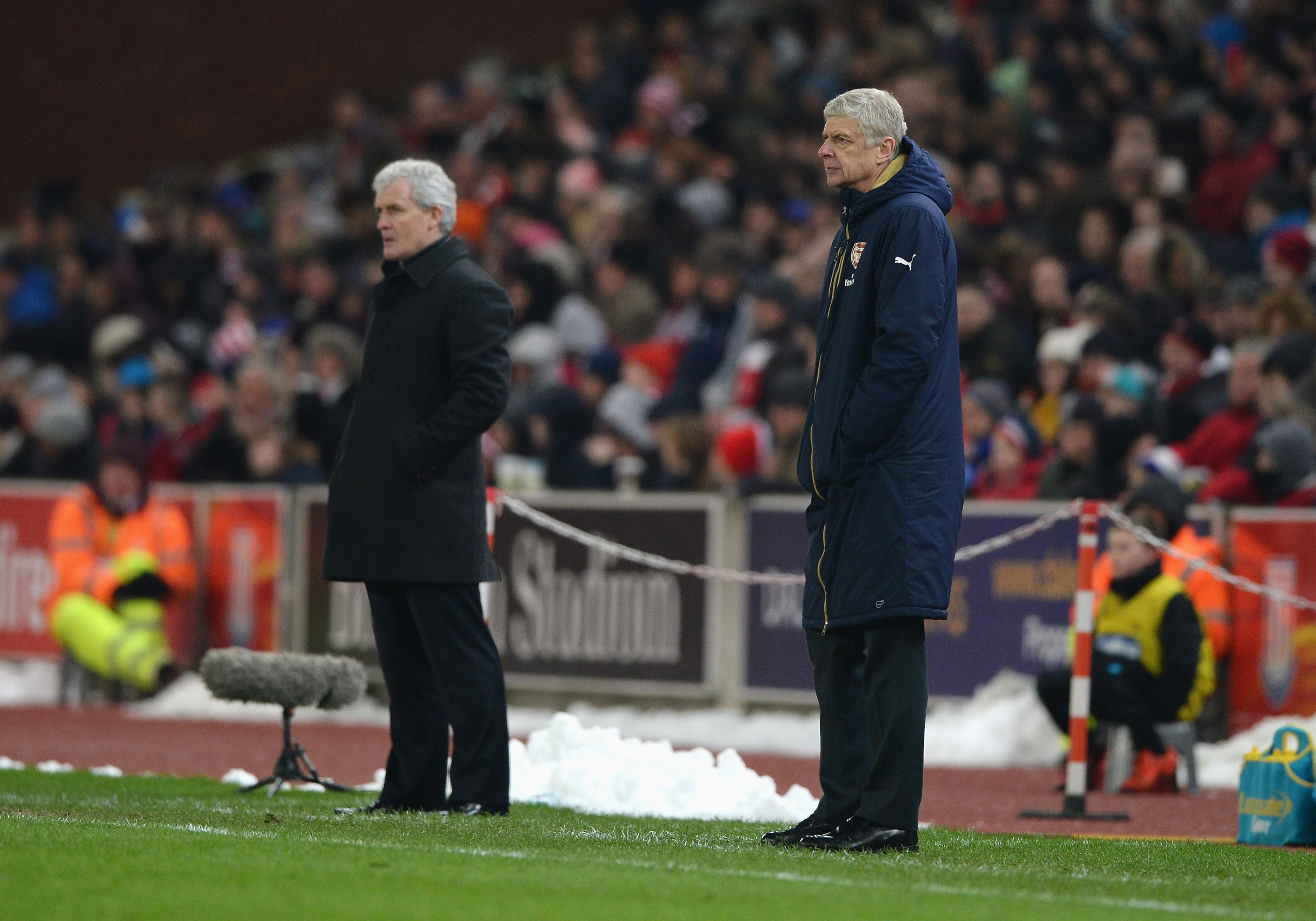 STOKE ON TRENT, ENGLAND - JANUARY 17: Arsene Wenger, manager of Arsenal looks on with Mark Hughes, manager of Stoke City during the Barclays Premier League match between Stoke City and Arsenal at Britannia Stadium on January 17, 2016 in Stoke on Trent, England. (Photo by Gareth Copley/Getty Images)