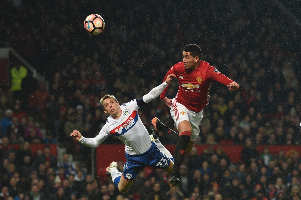 Manchester United's English defender Chris Smalling (R) heads the ball in to score their second goal during the English FA Cup fourth round football match between Manchester United and Wigan Athletic at Old Trafford in Manchester, north west England, on January 29, 2017. / AFP / Paul ELLIS / RESTRICTED TO EDITORIAL USE. No use with unauthorized audio, video, data, fixture lists, club/league logos or 'live' services. Online in-match use limited to 75 images, no video emulation. No use in betting, games or single club/league/player publications. / (Photo credit should read PAUL ELLIS/AFP/Getty Images)