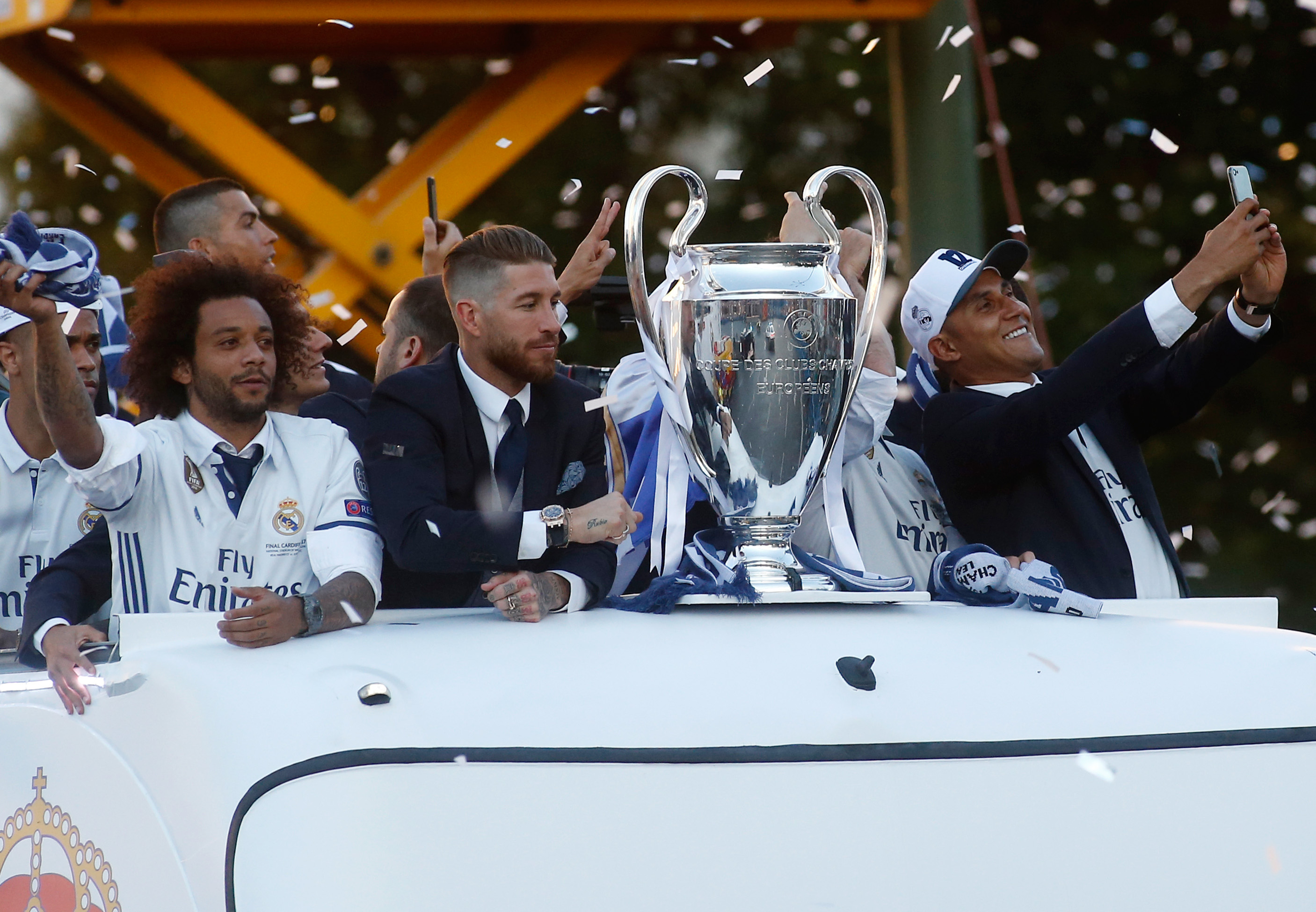 Real Madrid's Costa Rican goalkeeper Keylor Navas (R) takes a selfie photo with the trophy as he celebrates the team's win with Real Madrid's defender Sergio Ramos (C) and Real Madrid's Brazilian defender Marcelo ontop of a bus on Plaza Cibeles in Madrid on June 4, 2017 after the UEFA Champions League football match final Juventus vs Real Madrid CF held at the National Stadium of Wales in Cardiff on June 3, 2017. / AFP PHOTO / OSCAR DEL POZO        (Photo credit should read OSCAR DEL POZO/AFP/Getty Images)
