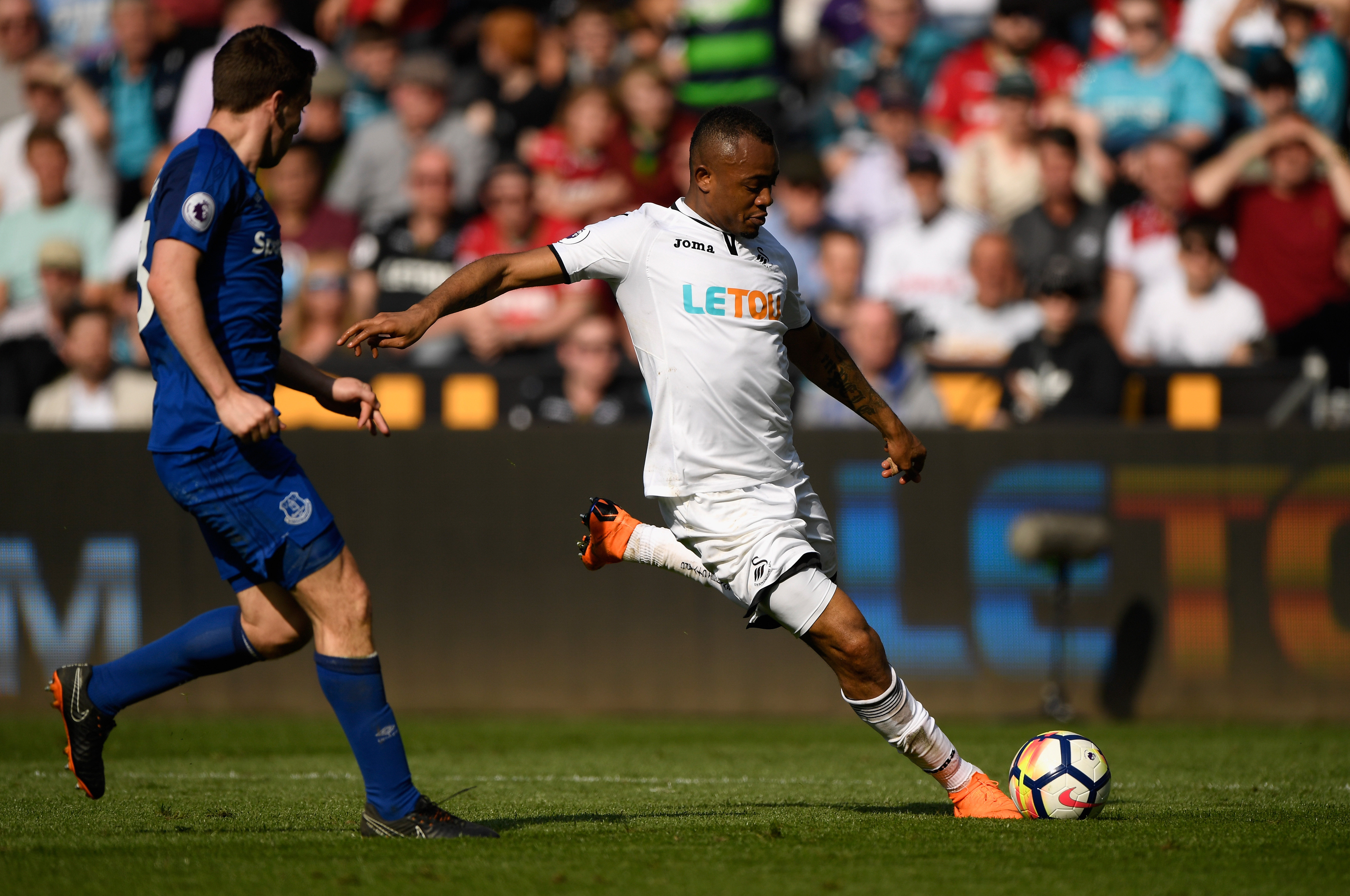 SWANSEA, WALES - APRIL 14: Swansea player Jordan Ayew shoots at goal despite the challenge of Phil Jagielka during the Premier League match between Swansea City and Everton at Liberty Stadium on April 14, 2018 in Swansea, Wales. (Photo by Stu Forster/Getty Images)