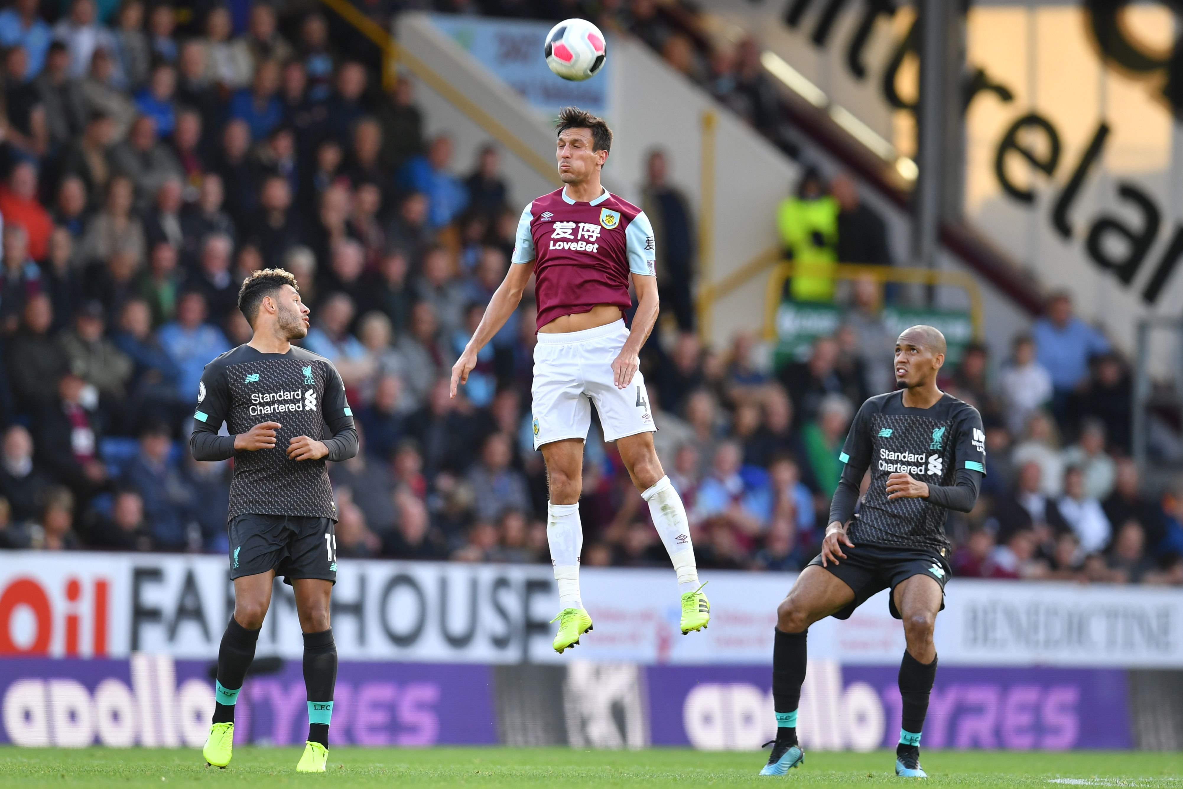Burnley's English midfielder Jack Cork (C) wins a header as Liverpool's English midfielder Alex Oxlade-Chamberlain (L) and Liverpool's Brazilian midfielder Fabinho (R) look on during the English Premier League football match between Burnley and Liverpool at Turf Moor in Burnley, north west England on August 31, 2019. (Photo by Paul ELLIS / AFP) / RESTRICTED TO EDITORIAL USE. No use with unauthorized audio, video, data, fixture lists, club/league logos or 'live' services. Online in-match use limited to 120 images. An additional 40 images may be used in extra time. No video emulation. Social media in-match use limited to 120 images. An additional 40 images may be used in extra time. No use in betting publications, games or single club/league/player publications. / (Photo credit should read PAUL ELLIS/AFP via Getty Images)