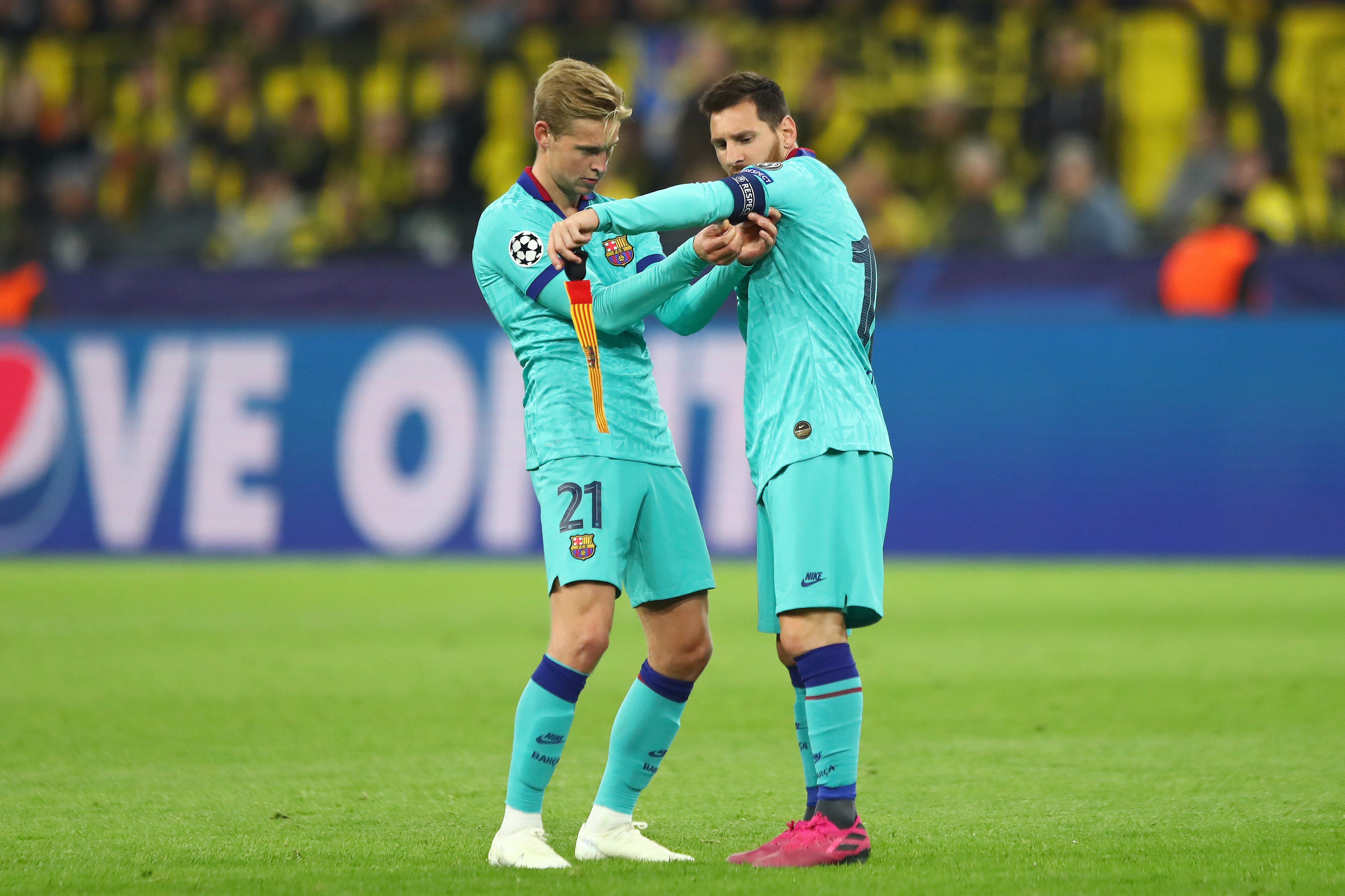 DORTMUND, GERMANY - SEPTEMBER 17: Frenkie de Jong of FC Barcelona assists Lionel Messi with the captain's armband during the UEFA Champions League group F match between Borussia Dortmund and FC Barcelona at Signal Iduna Park on September 17, 2019 in Dortmund, Germany. (Photo by Martin Rose/Bongarts/Getty Images)